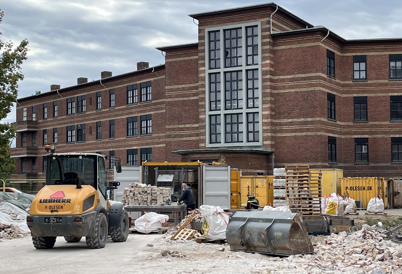 Foto fra byggeplass, murbygg i teglstein et gammelt sykehus som skal transformeres til bolig. Murstein renses og ombrukes. 