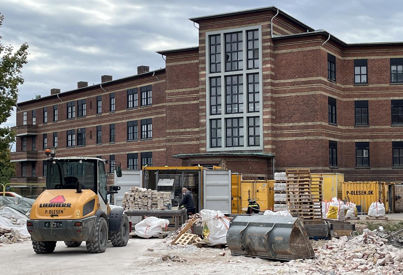 Foto fra byggeplass, murbygg i teglstein et gammelt sykehus som skal transformeres til bolig. Murstein renses og ombrukes. 