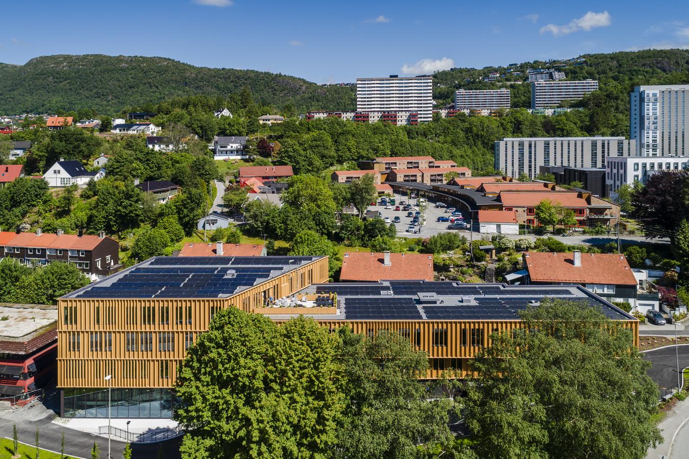 utvendig kontorbygg sett på avstand i terrenget. foto