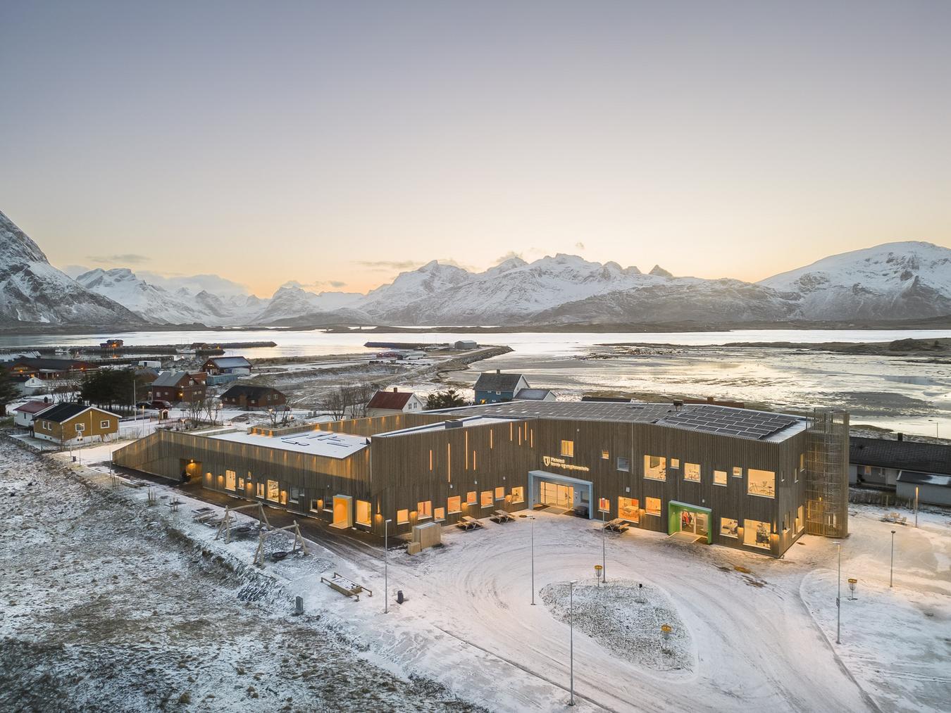 Skolebygg i massivtre. Oversiktsbilde i flott natur. Foto 