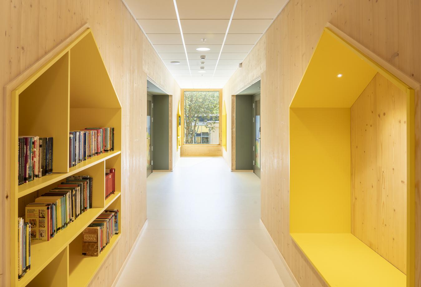 Korridor i trämaterial med gula bokhyllor. Foto
