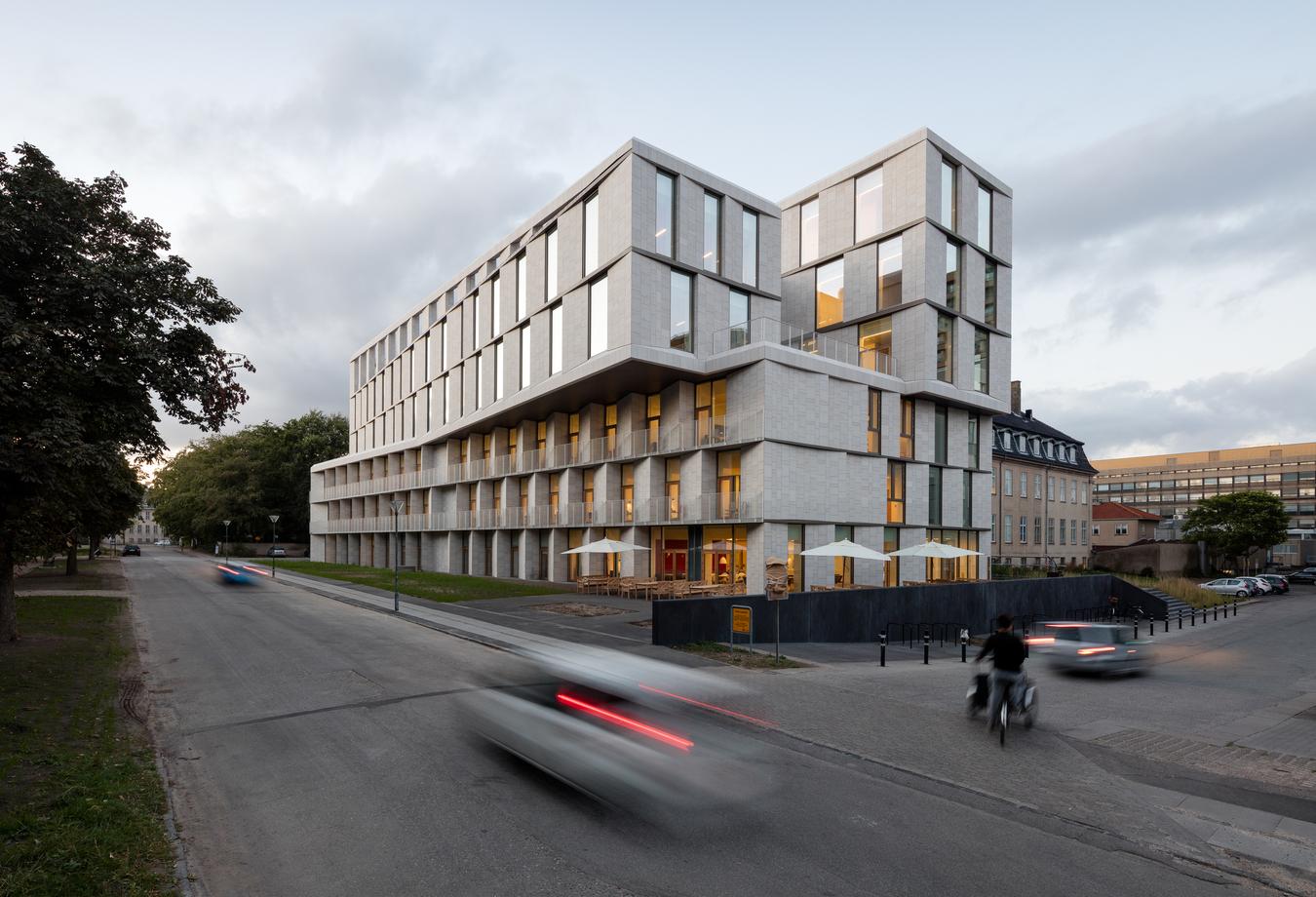 Stone building in a street environment with cars and cyclist. Photo