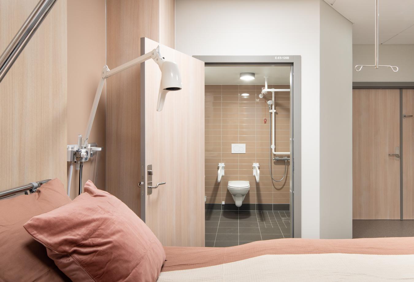 Patientværelse og badeværelse i beige toner. Foto